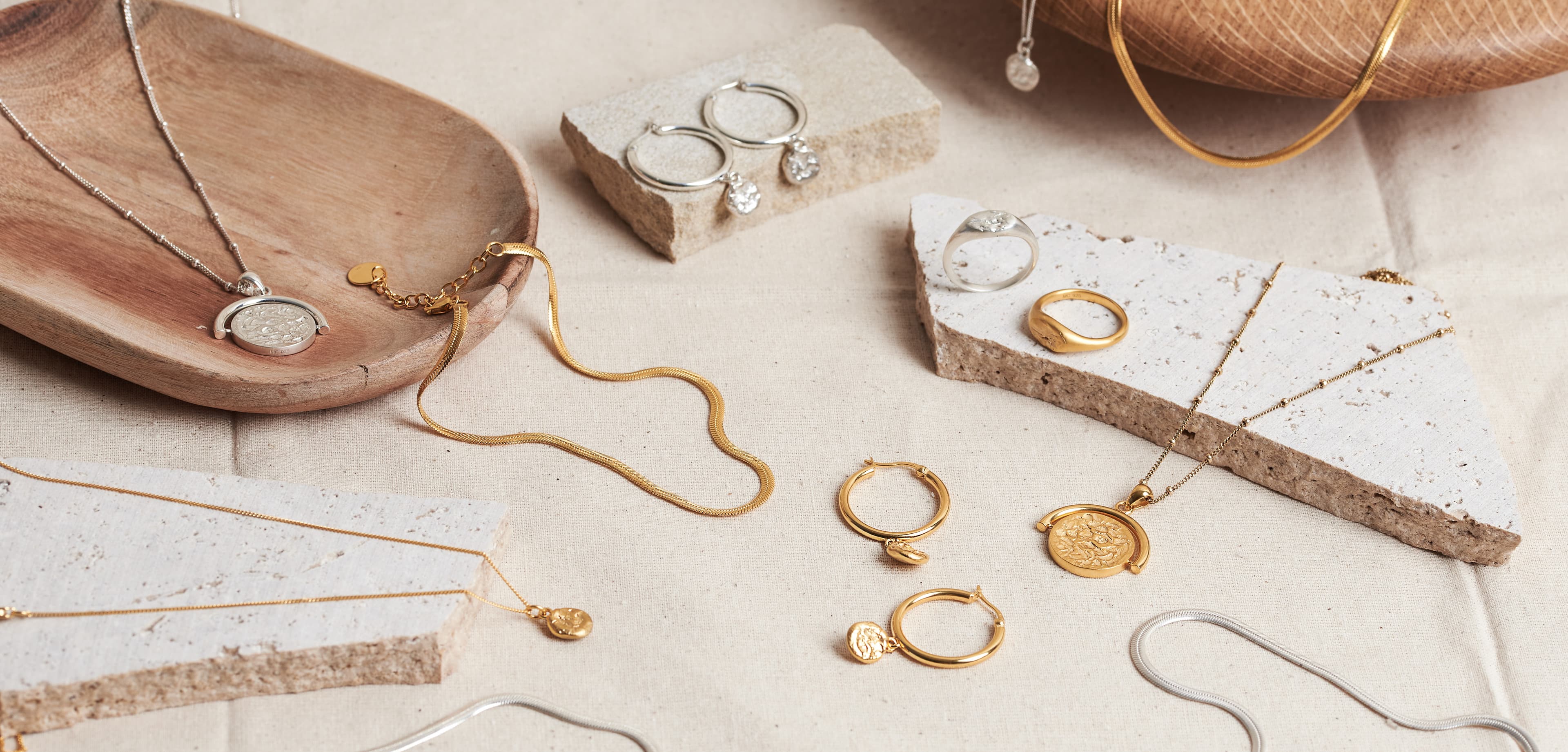 A flat lay of finished gold and silver pieces on cream linen